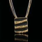 Black cord necklace with square black pendant and three gold-toned hammered bars