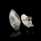 Arracades de plata amb forma de llàgrima martellejada amb detall de tancament de papallona visible en una arracada