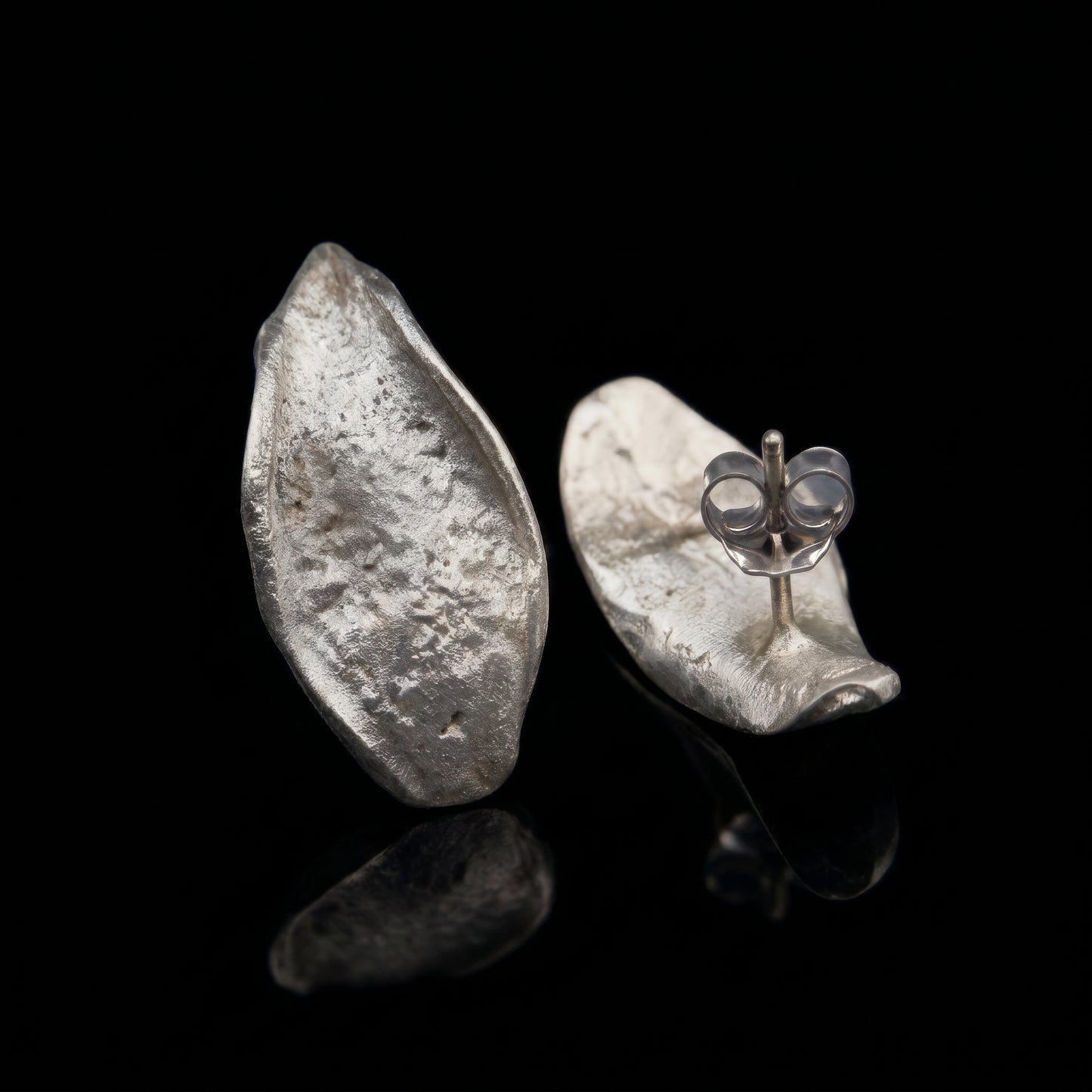 Hammered teardrop silver earrings with visible butterfly clasp detail on one earring