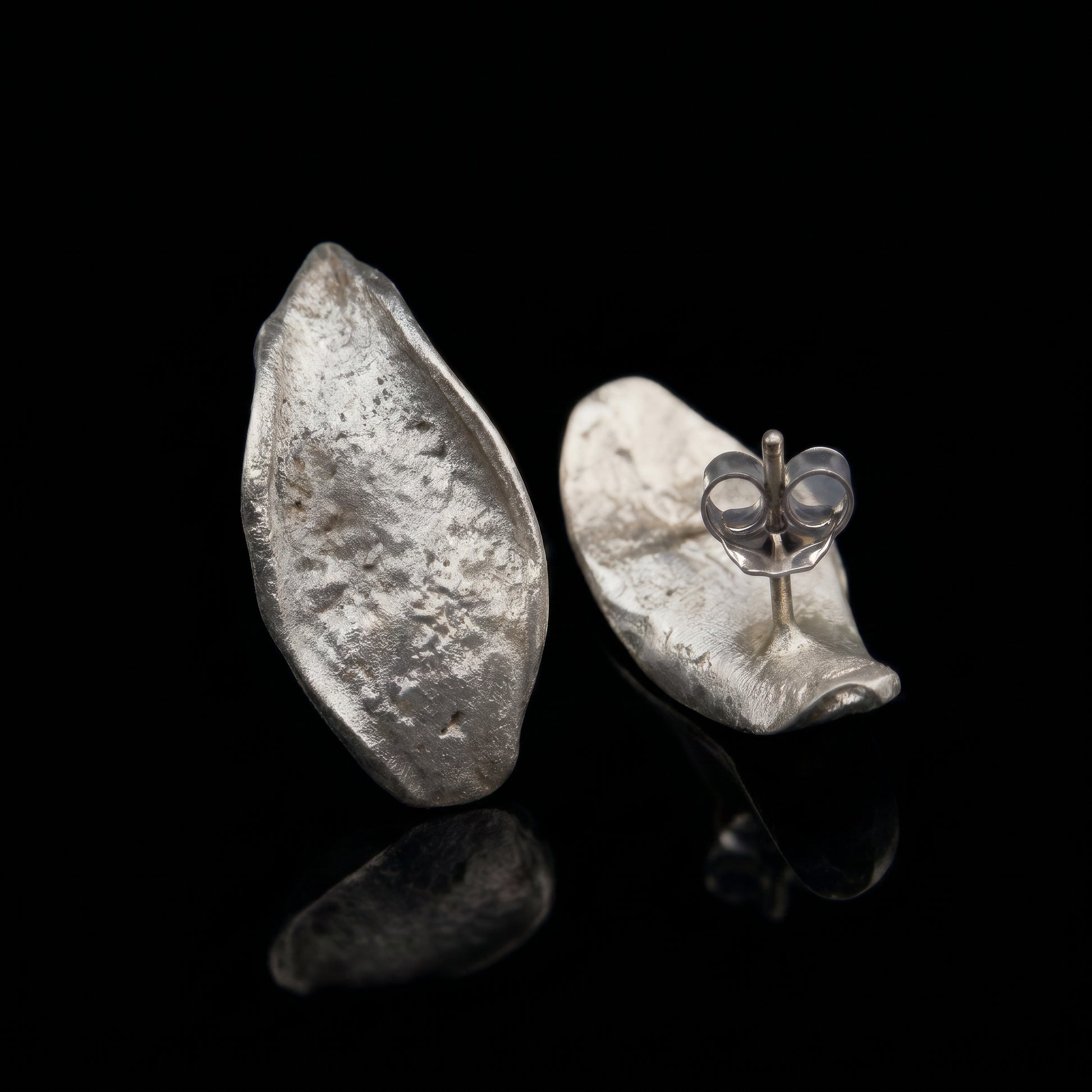 Hammered teardrop silver earrings with visible butterfly clasp detail on one earring