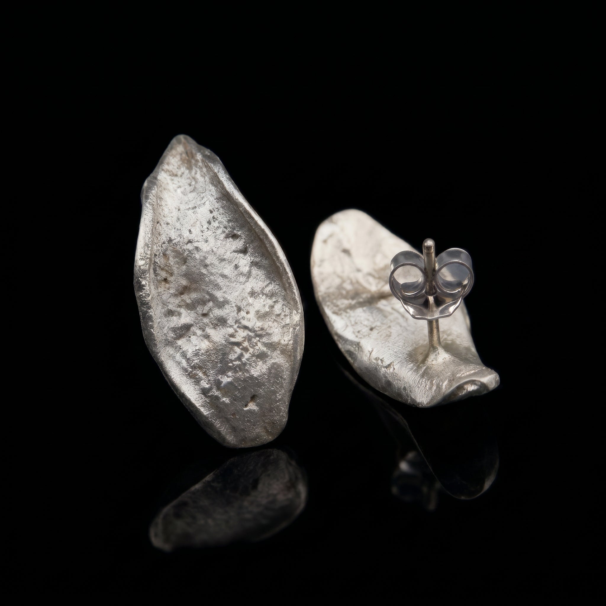 Hammered teardrop silver earrings with visible butterfly clasp detail on one earring
