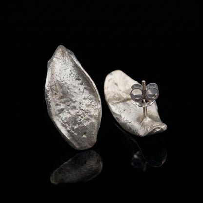 Hammered teardrop silver earrings with visible butterfly clasp detail on one earring