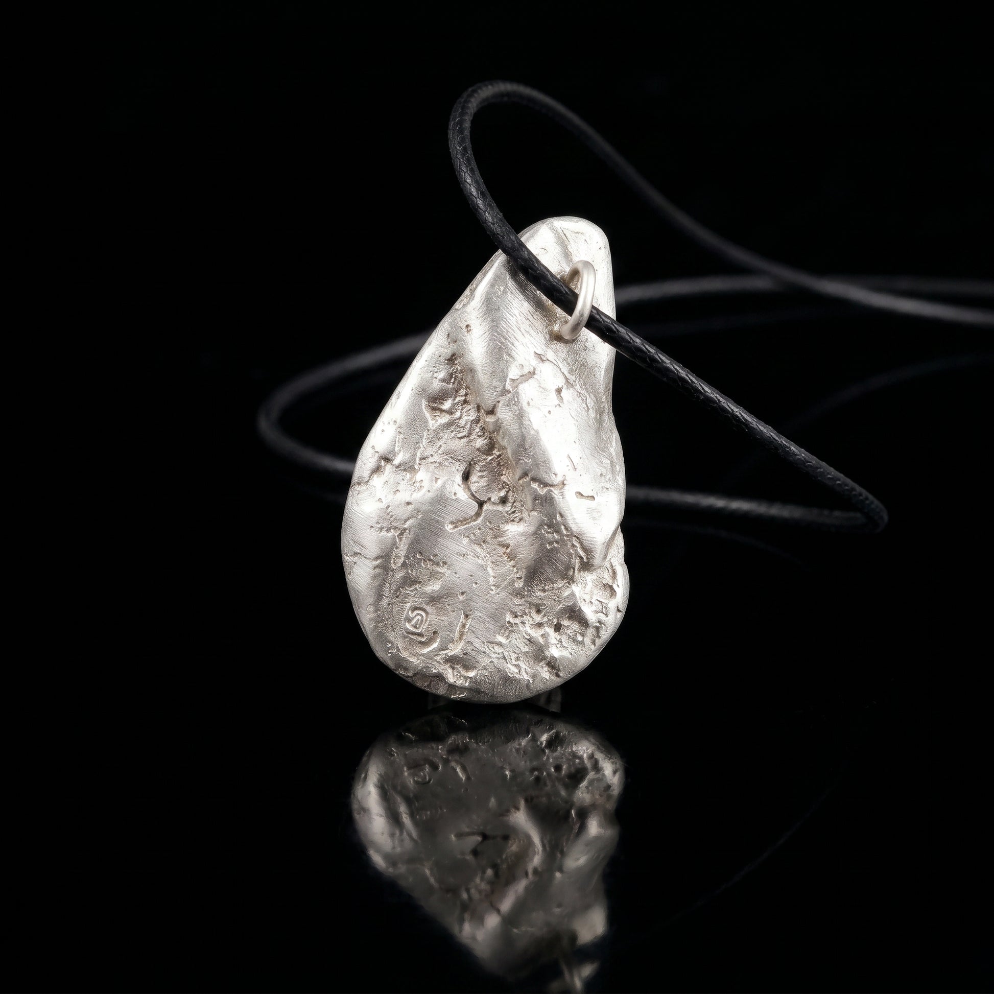Silver-tone hammered teardrop pendant on black cord with metal loop