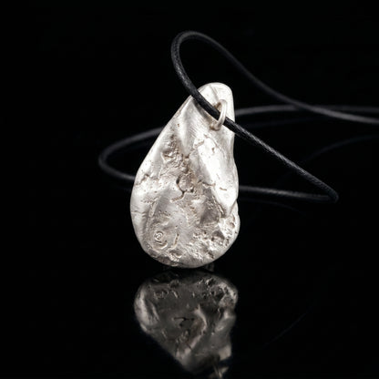 Silver-tone hammered teardrop pendant on black cord with metal loop