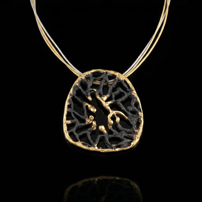 Orbis pendant with dark round filigree and gold-toned rim on thin chain