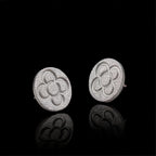Pendientes de botón redondos plateados con patrón de flor de cuatro pétalos en relieve y postes