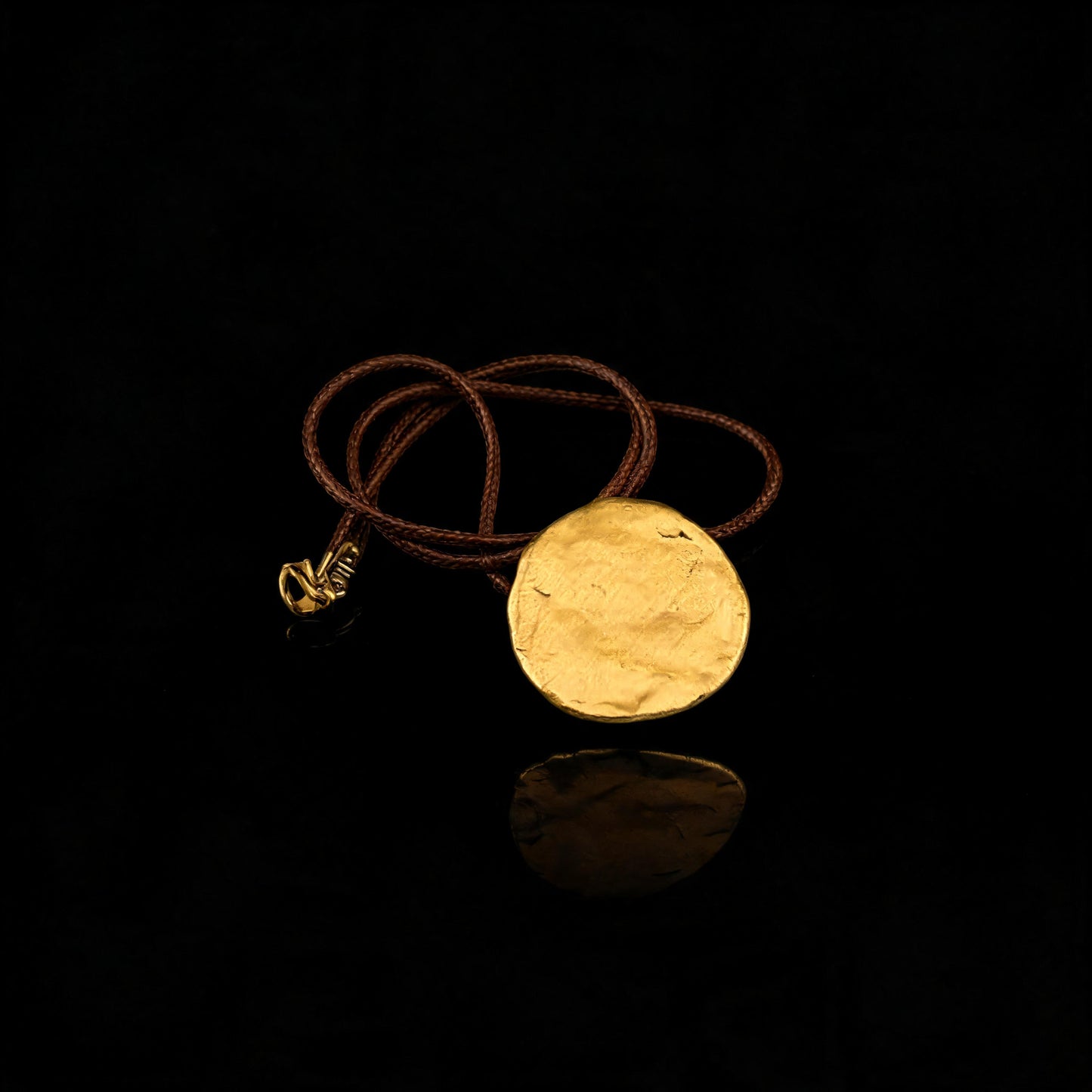 Gold round disc pendant necklace with brown cord and reflective surface