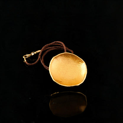 Gold-tone round pendant necklace with brown braided cord and chain loop