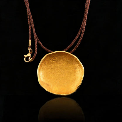 Gold-tone round pendant necklace on brown cord, lobster clasp visible