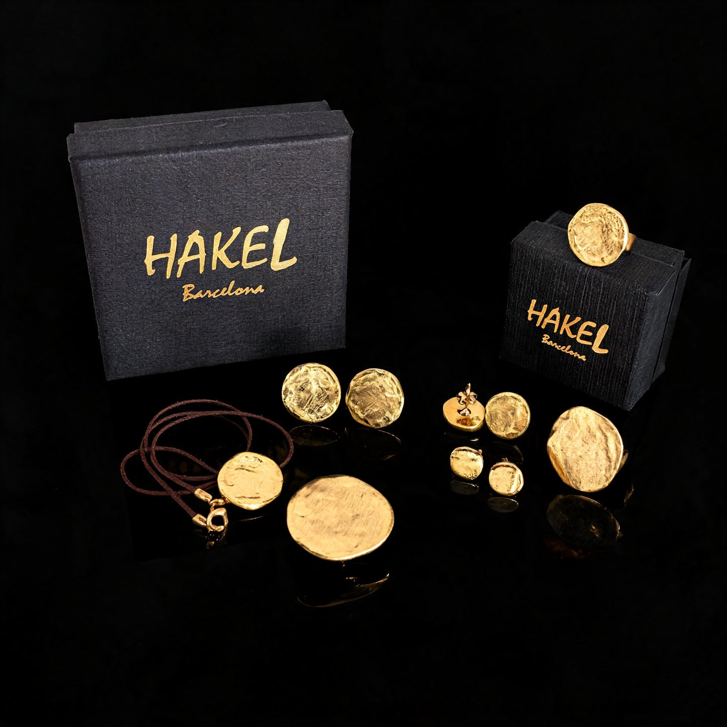 Gold stud and drop earrings set with small round discs, shown with HAKEL boxes