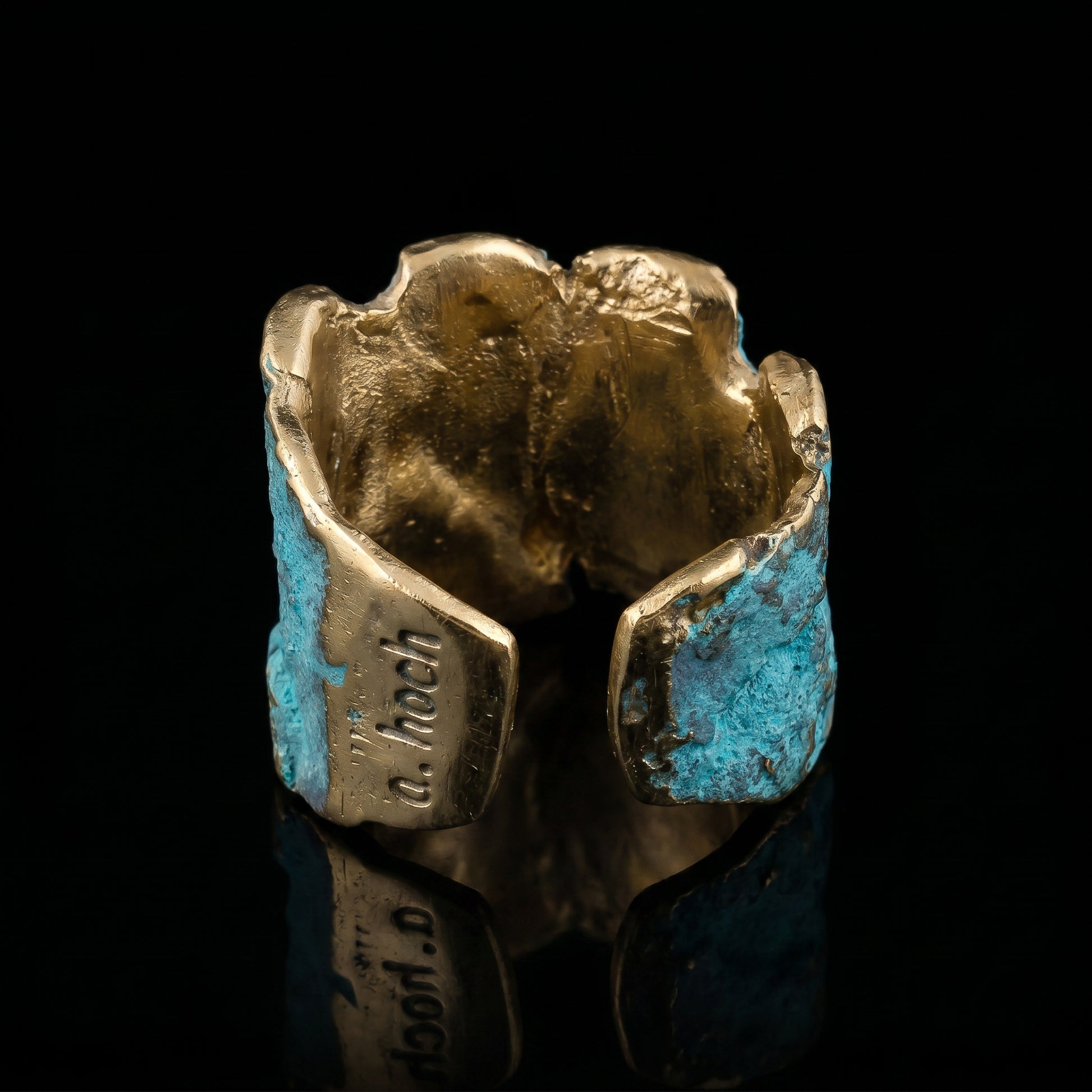 Gold-tone cuff ring with turquoise-blue stone and dark base