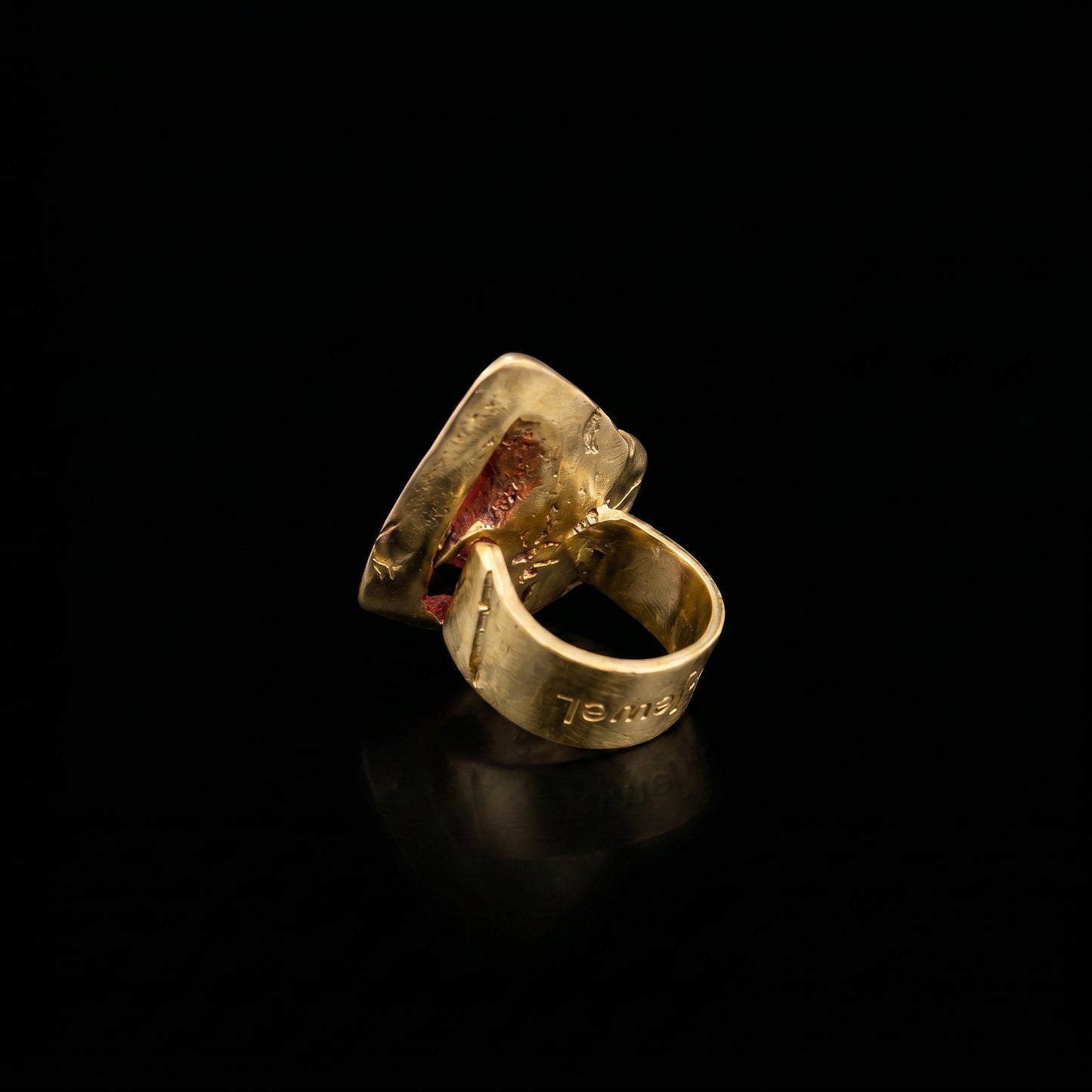 Gold-tone ring with red gem accent and engraved inner band