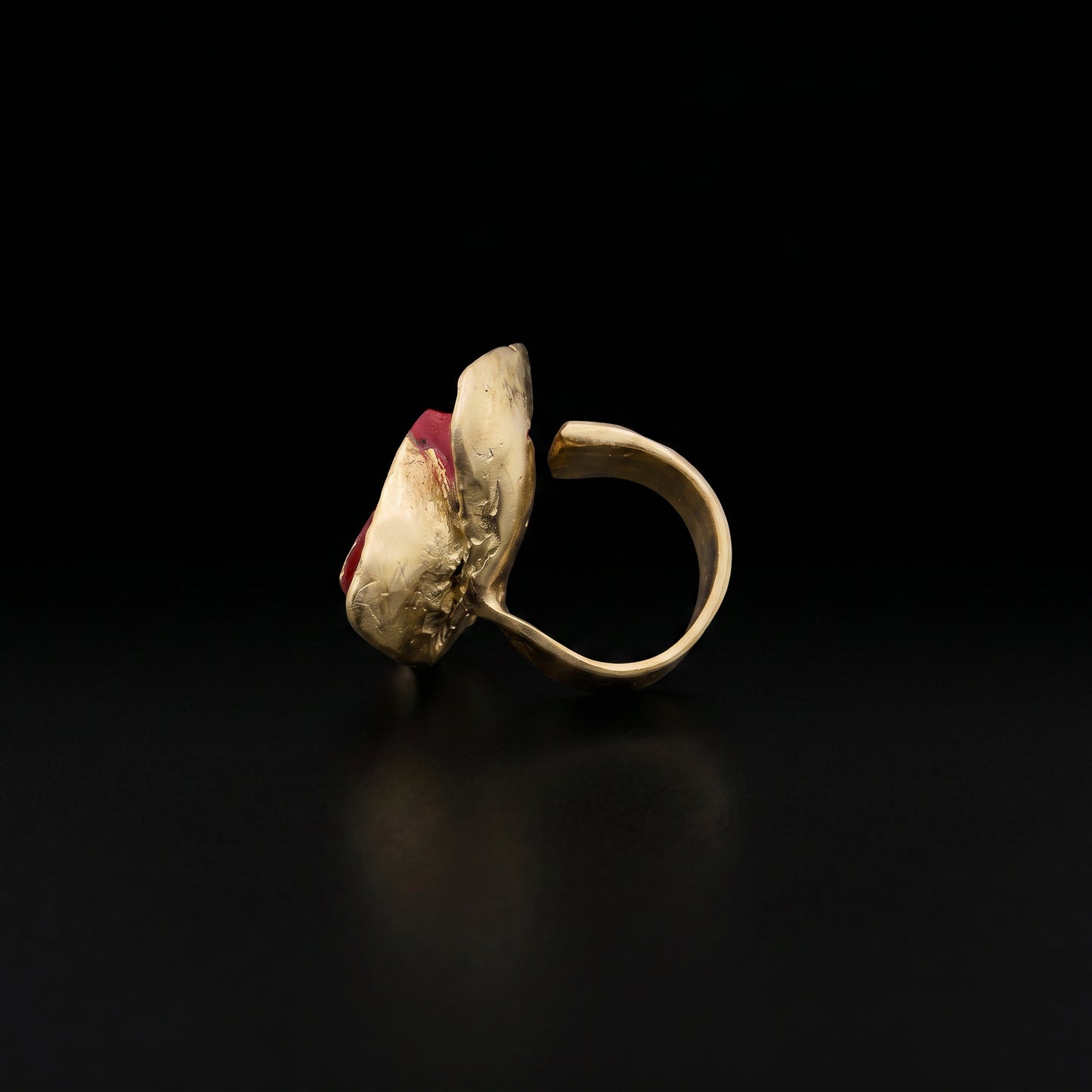 Gold-tone ring with red stone top and open side setting