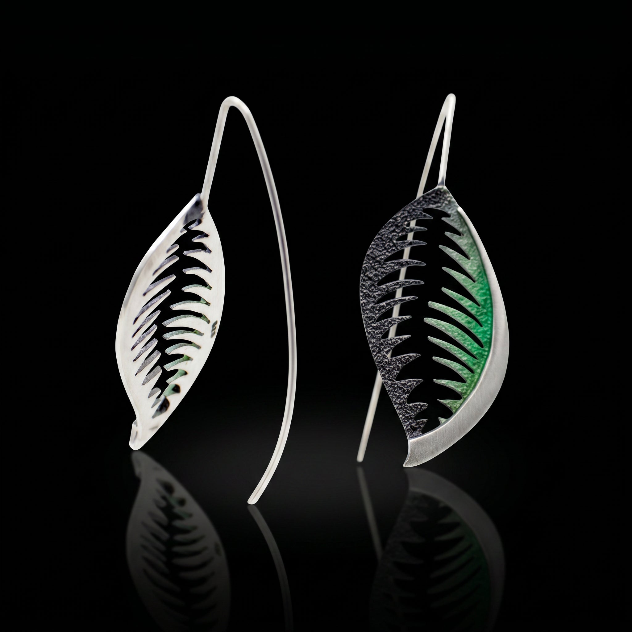 Pair of veined leaf earrings with black and green accents, silver-tone curved backs.