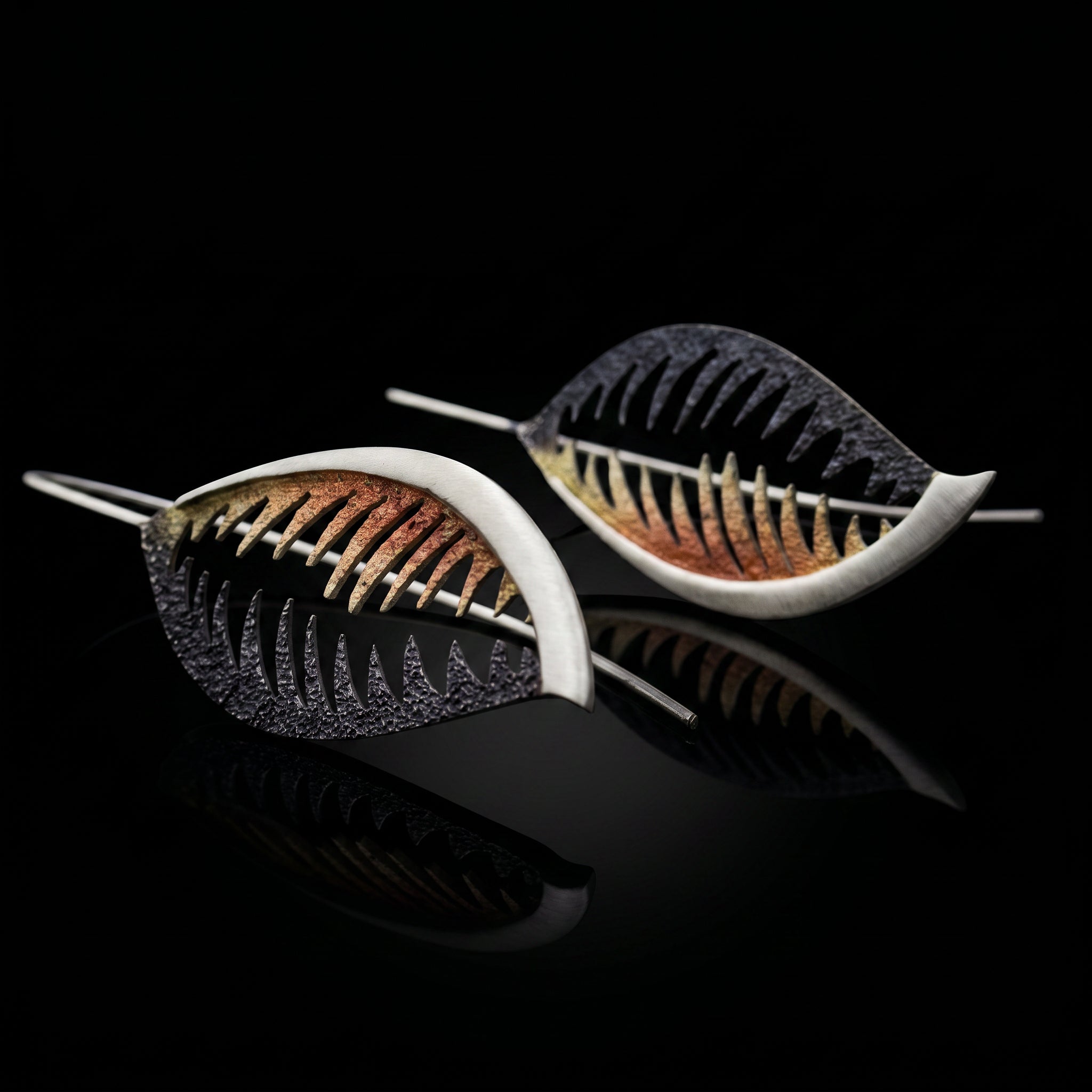 Veined leaf-shaped earrings with bronze-orange and black detail, silver-tone wire hooks.