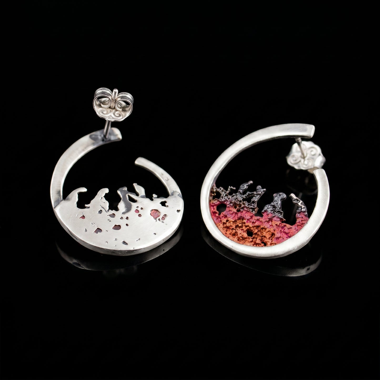 Silver hoop earrings with red resin splash over a light base