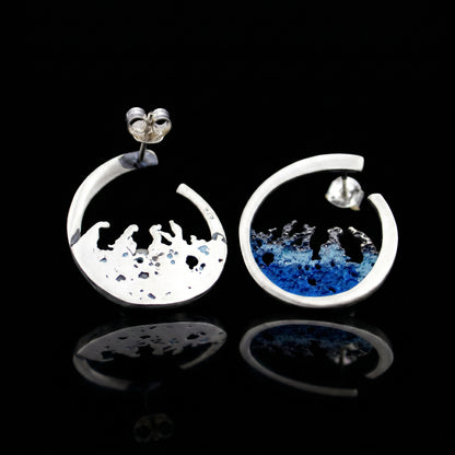 Silver hoop earrings with blue resin splash over a light base