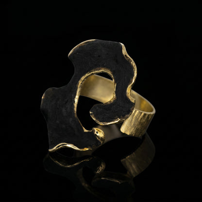 Dark blue and gold openwork ring with a wide sculpted band and cutout.