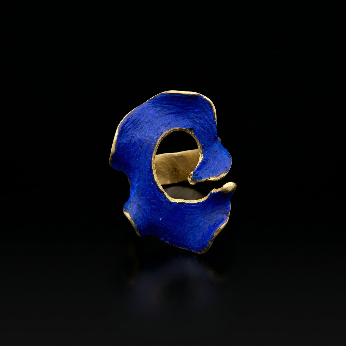 Blue statement ring with irregular openwork design and gold-tone band.