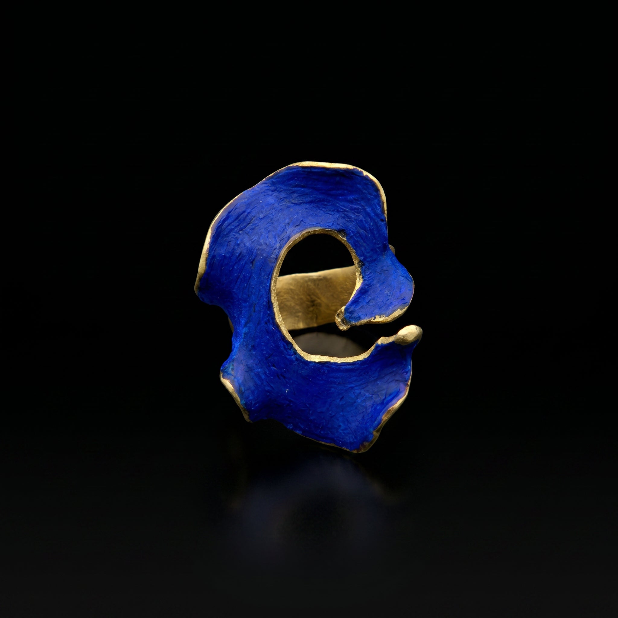 Blue statement ring with irregular openwork design and gold-tone band.