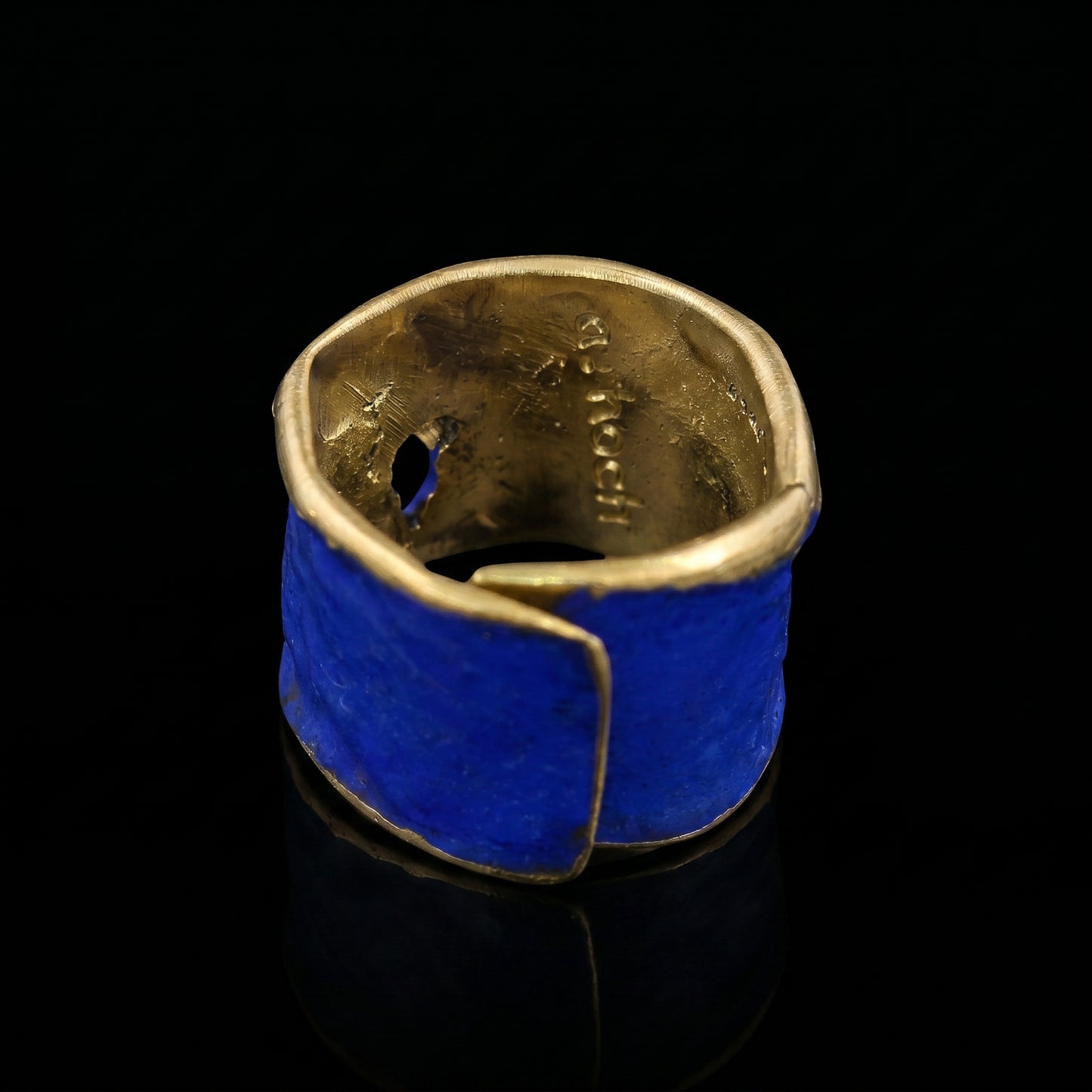 Blue enamel ring with gold-toned inner band and curved, textured design