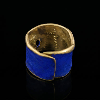 Blue enamel ring with gold-toned inner band and curved, textured design