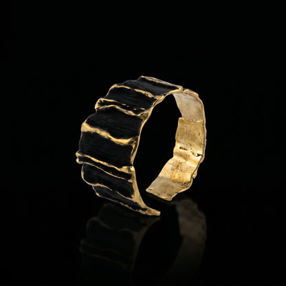 Sculpted gold-tone cuff bracelet with dark ridged segments and gold edges
