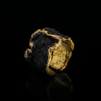 Anillo tono oro con piedra oscura y borde dorado rugoso