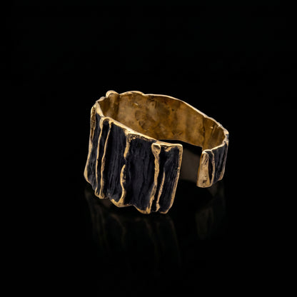 Wide sculpted cuff bracelet with gold-tone outer sides and dark ridged front