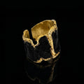 Anillo brazalete tono oro con centro de piedra oscura y bordes exteriores texturizados