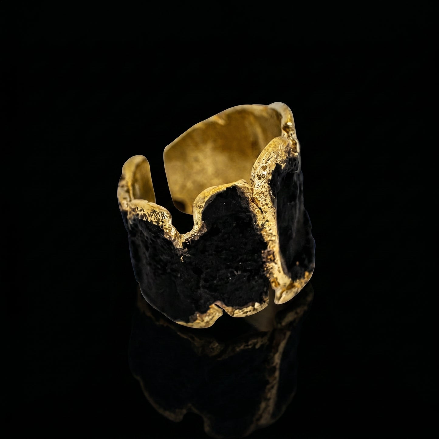 Gold-tone cuff ring with dark stone center and textured outer edges
