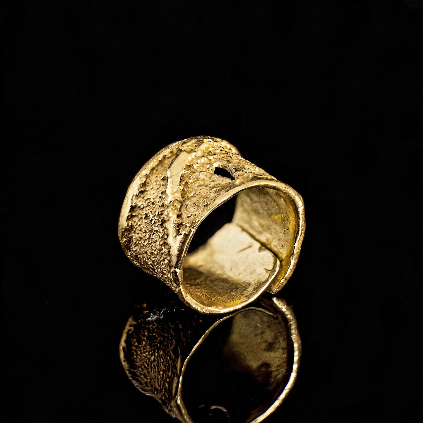 Gold textured ring with reflective, hollow oval interior and speckled metal finish