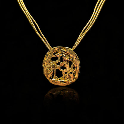 18K gold void pendant with textured circular design, on gold chain
